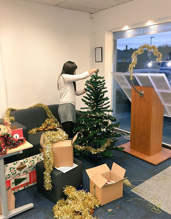 women setting up a Christmas tree in her office 