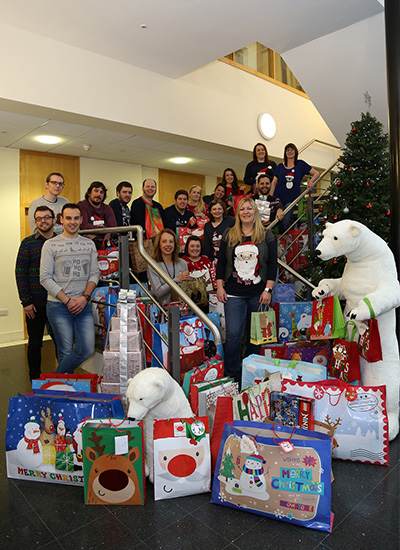 group photo of everyone in the office with loads of presents 
