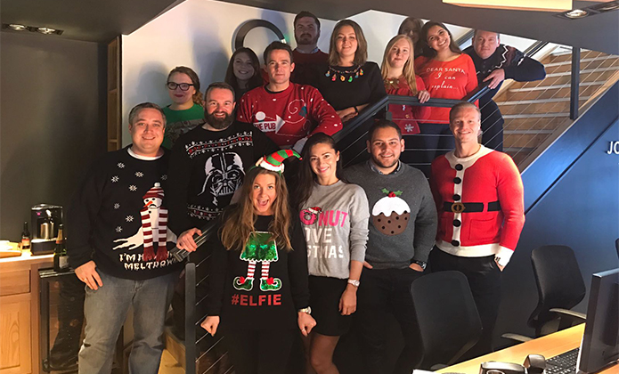 office photo with people standing on stairs with Christmas jumpers on 