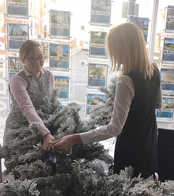two women setting up a Christmas tree