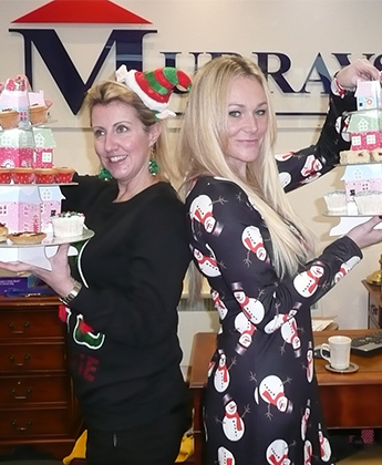 2 girls holding cakes dressed in Christmas dresses