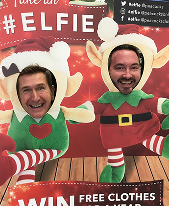 2 men in a cut out of  elf taking a photo 
