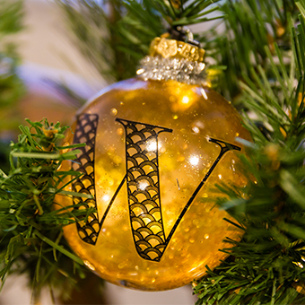 a gold ball ball on a Christmas tree with the letter W on it 
