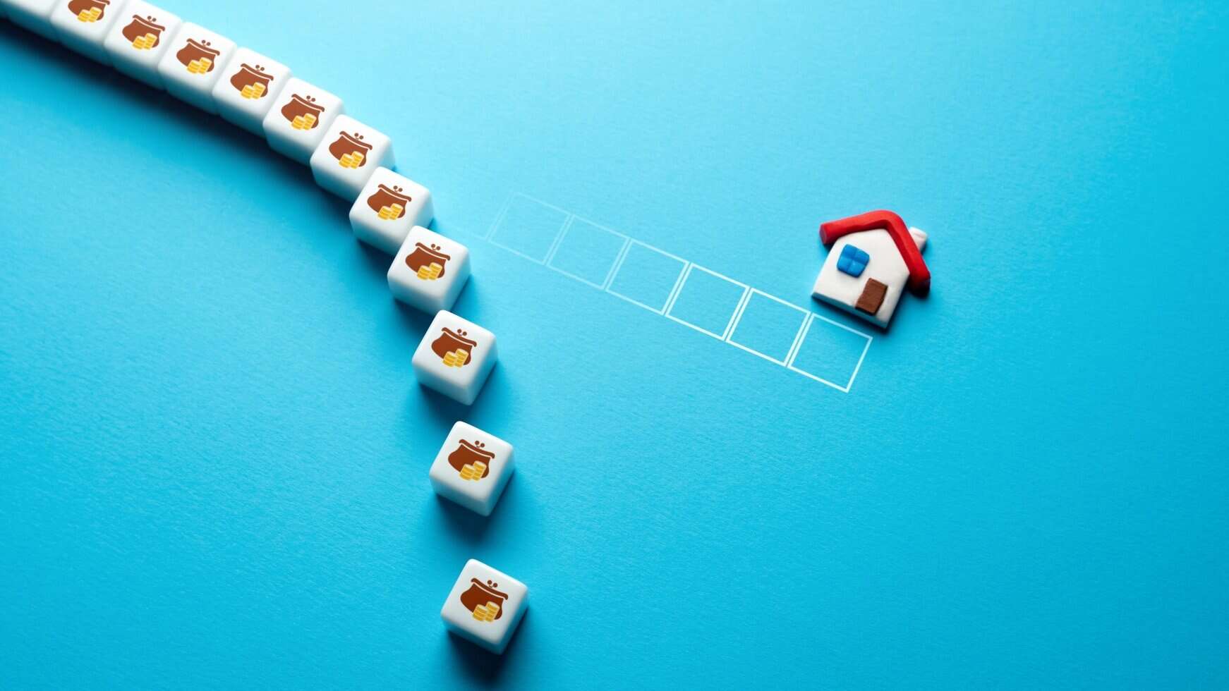 Miniature house and building blocks on blue background for property planning.