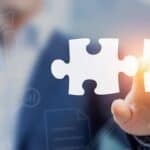 An image of a person connecting puzzle pieces representing real estate solutions and property market.